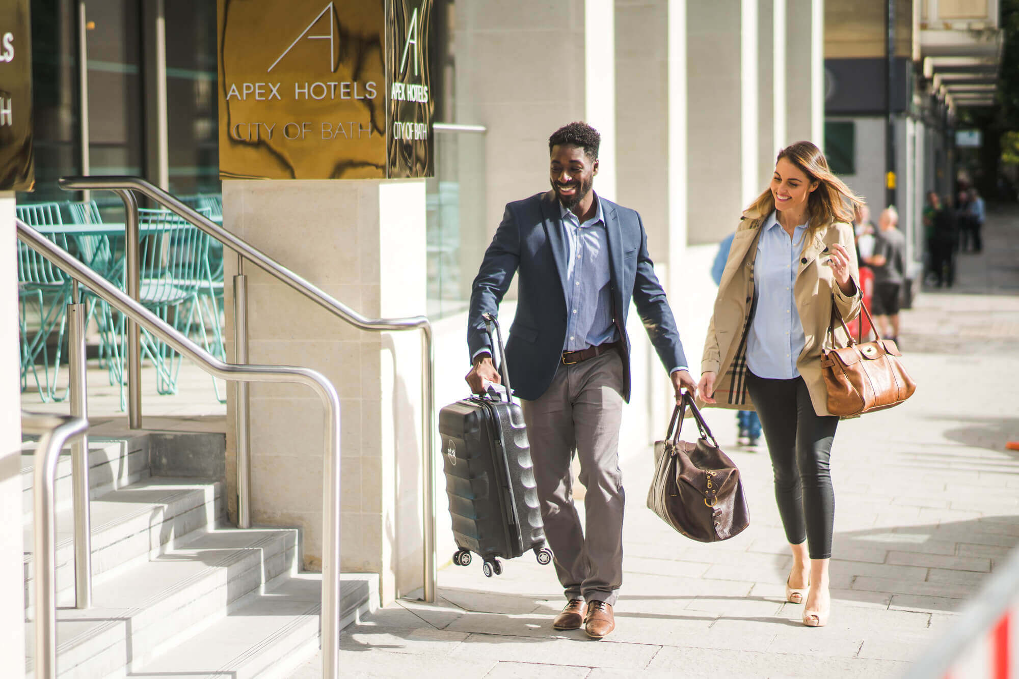Apex concierge staff helping a guest into Apex City of Bath Hotel with her bags