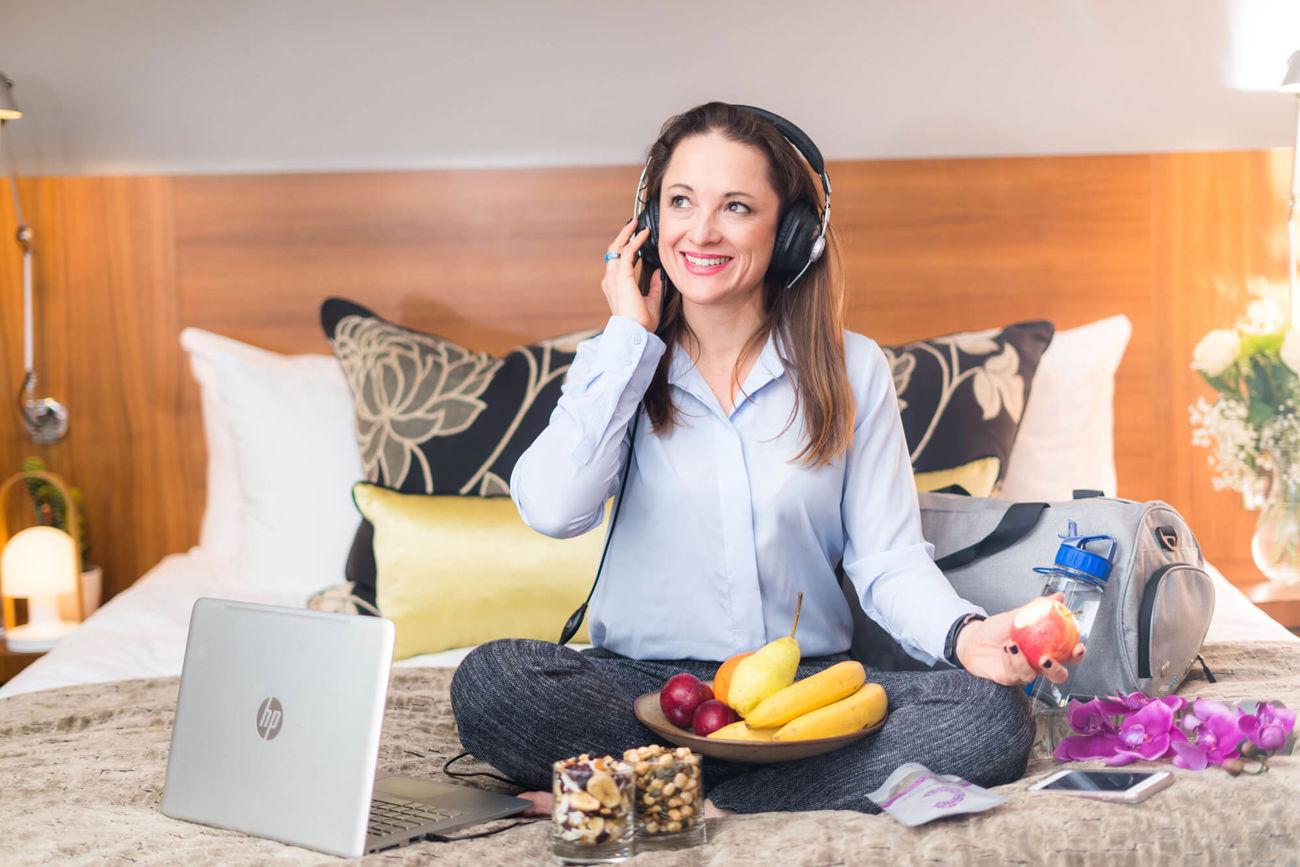 Celynn Morin sitting on bed listening to podcast with headphones on
